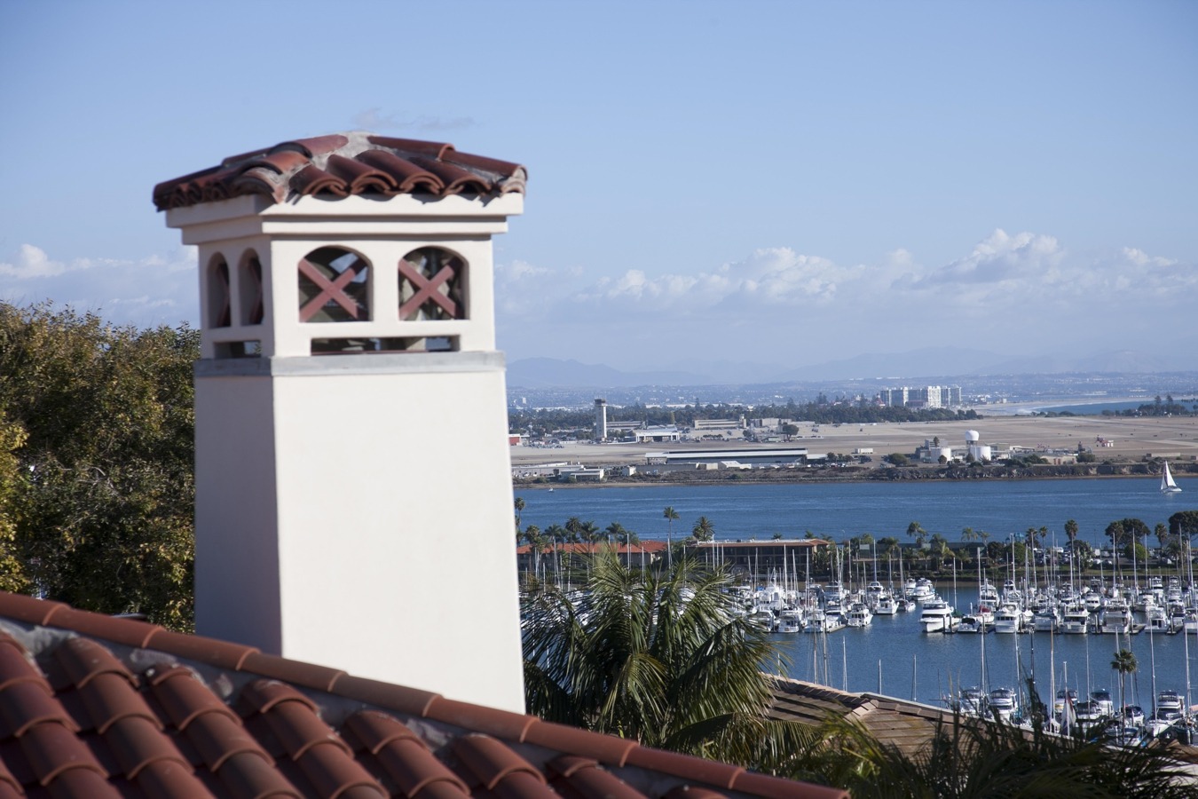 A scenic view of the harbor and marina from a rooftop, showcasing boats and water under a clear sky.