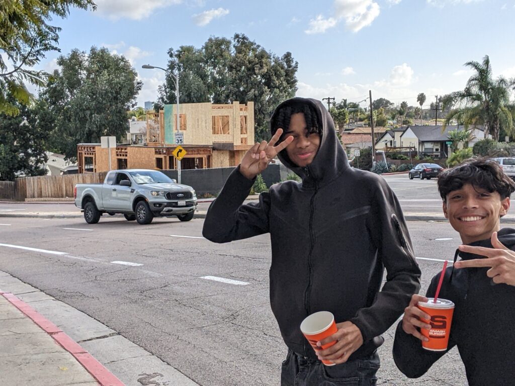 Two young men smiling and posing together for a photo on a city street.